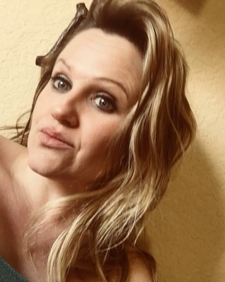 Femme trans en bustier vert, cheveux blonds, regardant l'appareil avec un air pensif