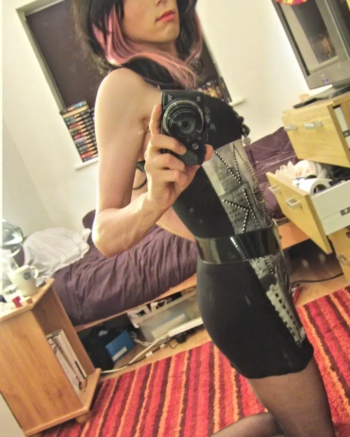 Femme trans en haut blanc, assise sur une chaise, regard direct, cheveux longs, ambiance intime